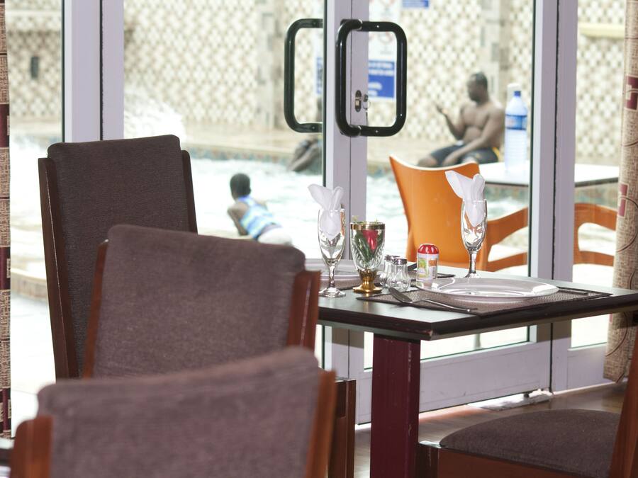 Un comedor con una mesa dispuesta para dos personas, vistas al patio de una piscina y una cortina estampada.