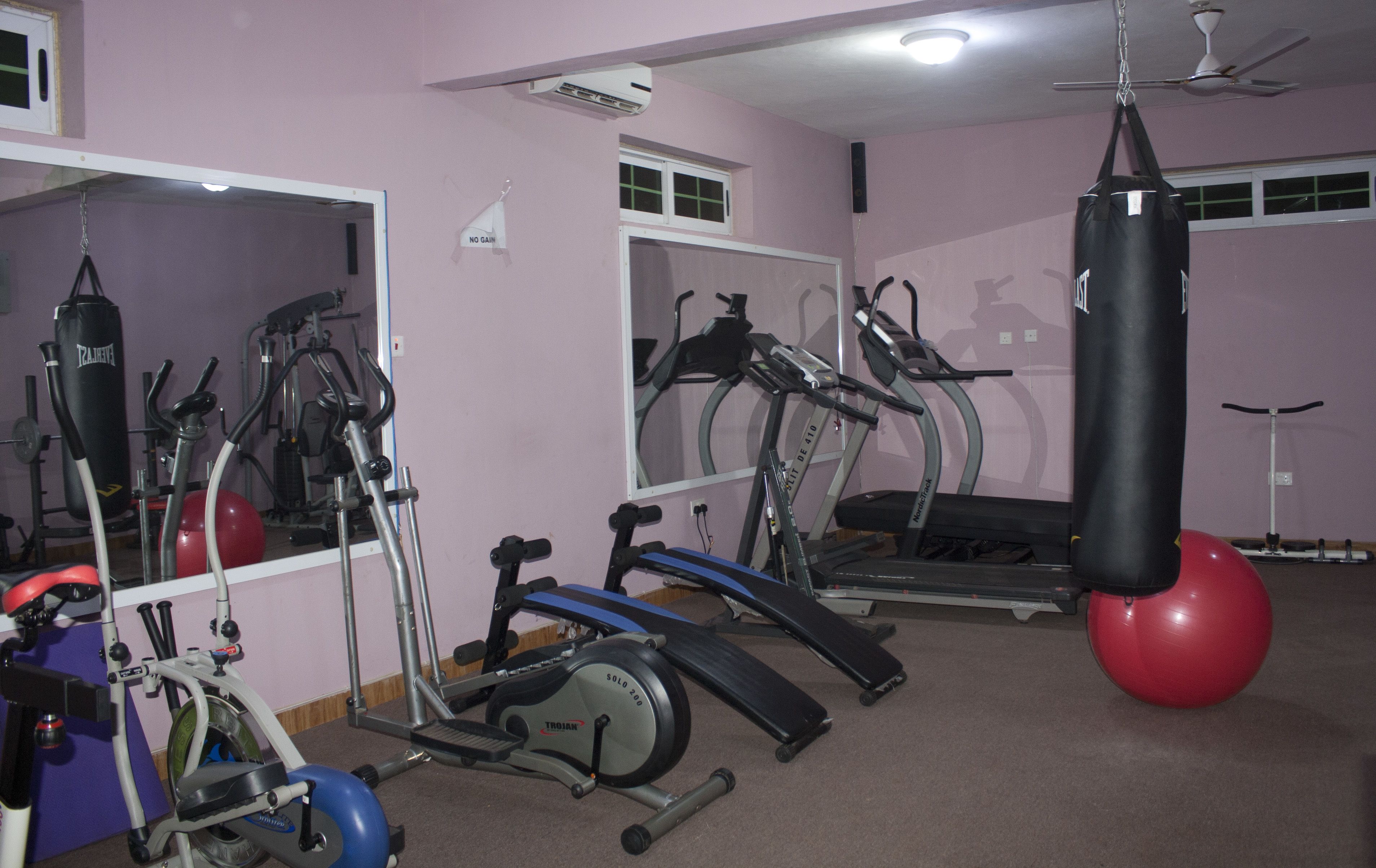 A gym with various exercise equipment, including treadmills, stationary bikes, and a punching bag.