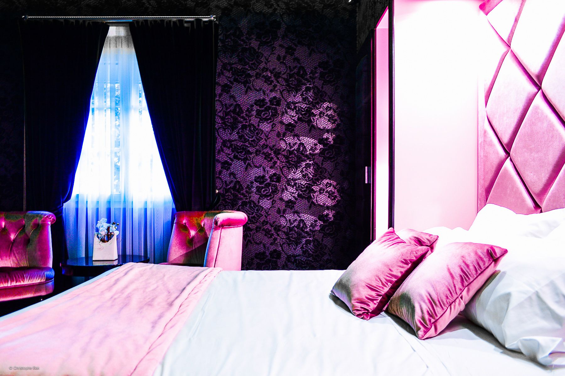 A bedroom with a bed, a chair, and a window with curtains.