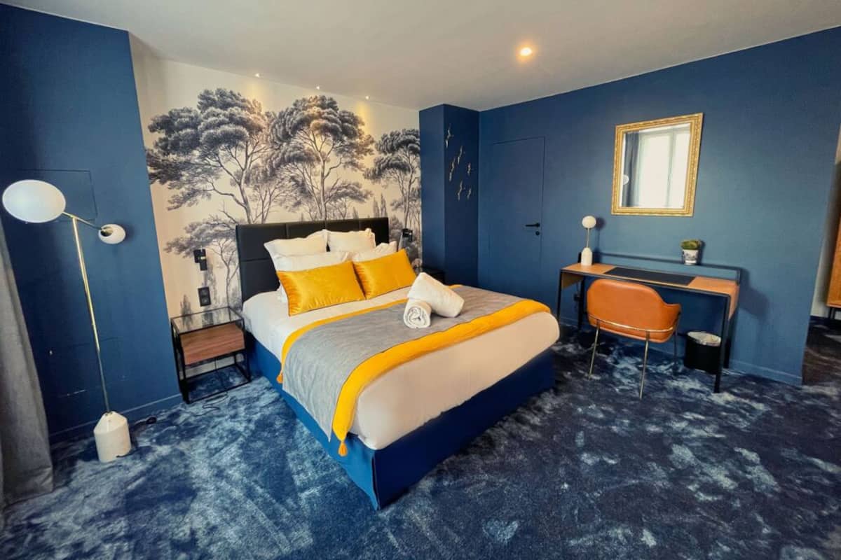 A bedroom with a bed, bedside table, chair, and a desk.