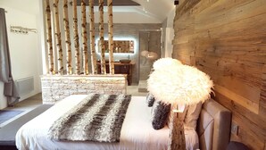 A modern bedroom with a stone fireplace, a fluffy white pouf, and a stone bench. - Les Granges d'Haillancourt (Saint-Crepin-Ibouvillers)