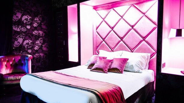 A modern bedroom with a large bed, a tufted armchair, and a patterned wall. - Les Granges d'Haillancourt (Saint-Crepin-Ibouvillers)