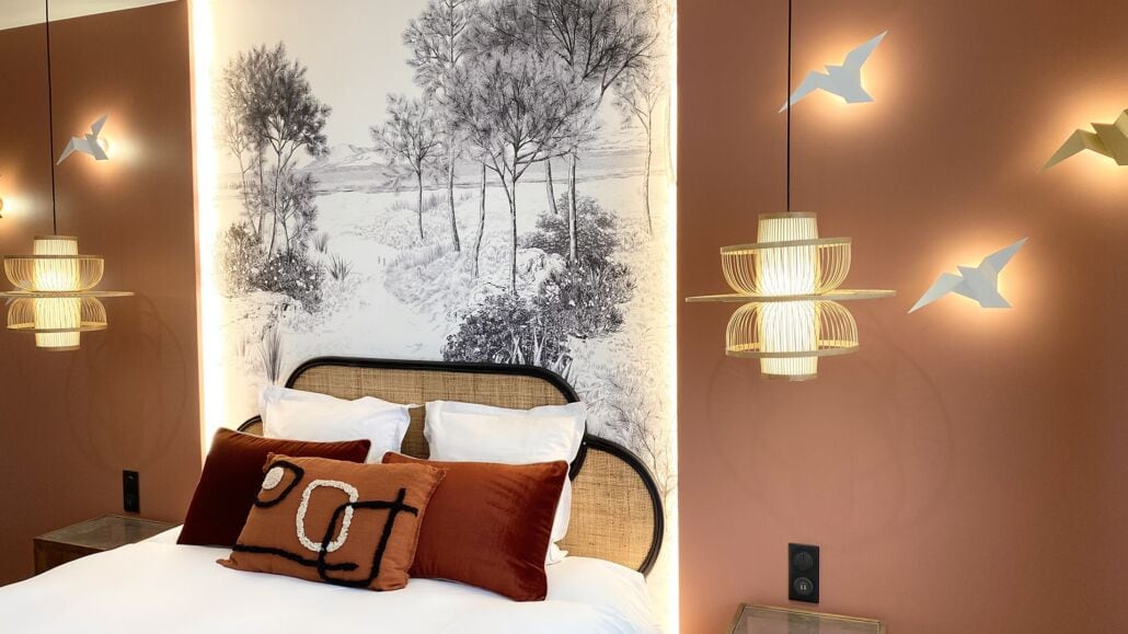 Een slaapkamer met een bed, kussens, een hoofdeinde en wandlampen.
