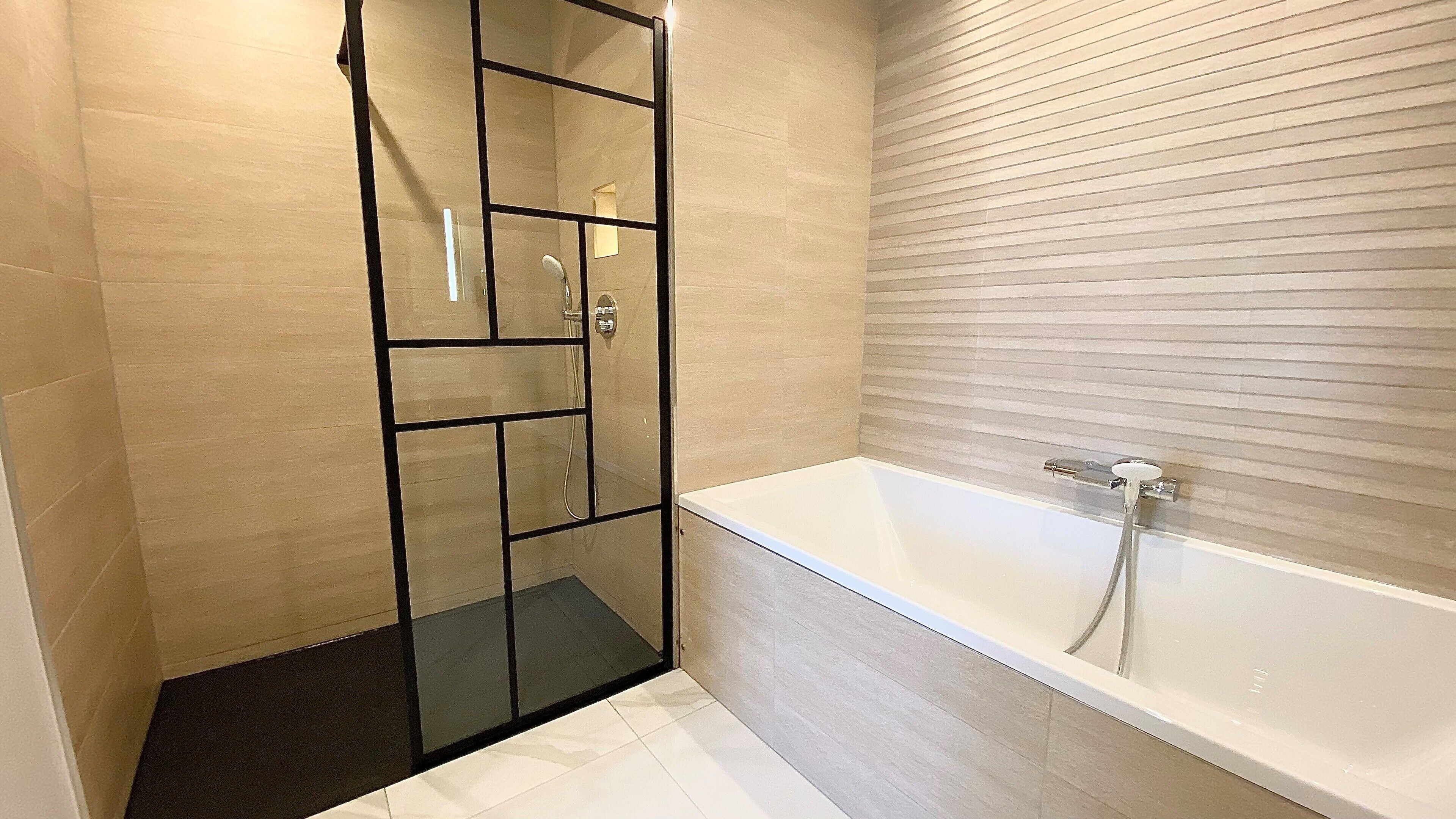A modern bathroom with a glass-enclosed shower, a bathtub, and a tiled floor.