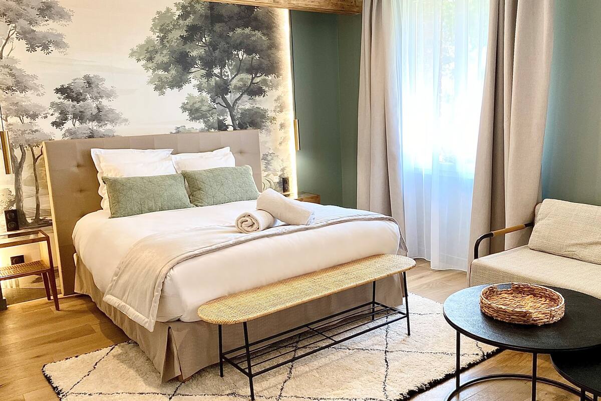 A neatly arranged bedroom with a bed, bedside table, and a seating area with a table and chair.