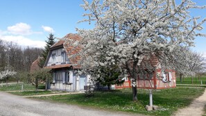 A traditional house with a sloped roof, a visible chimney, and a small porch with a bench. - Les Loges de l'Ecomusée D'Alsace (Ungersheim)