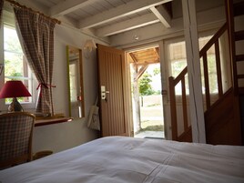 Un dormitorio con cama, una silla, una lámpara, un espejo y una puerta abierta que da al exterior.