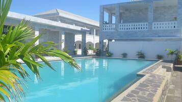 Relax by the serene pool surrounded by a modern architectural structure with a flat roof and arches.