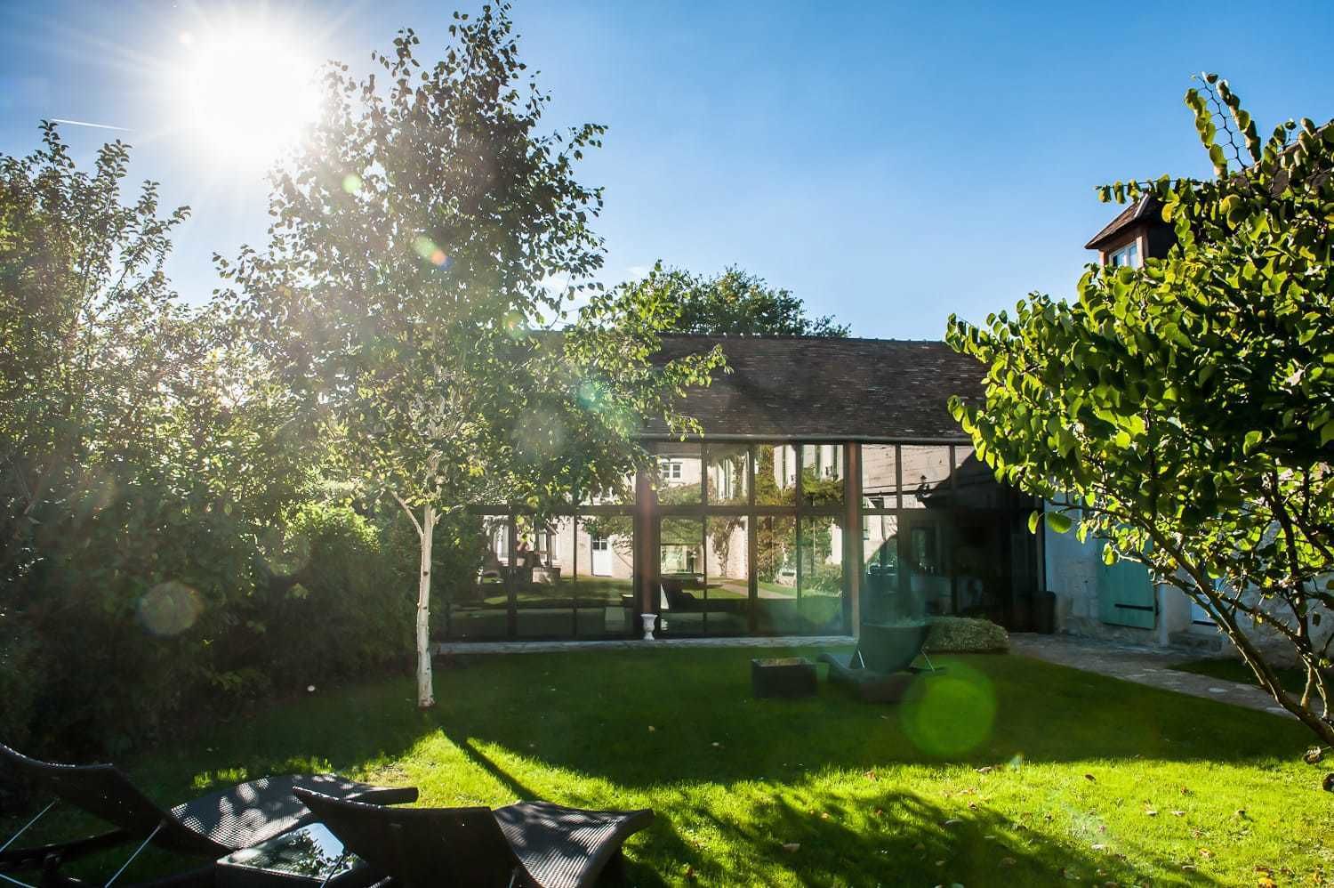 A glass-enclosed building with a lawn and trees in the foreground.
