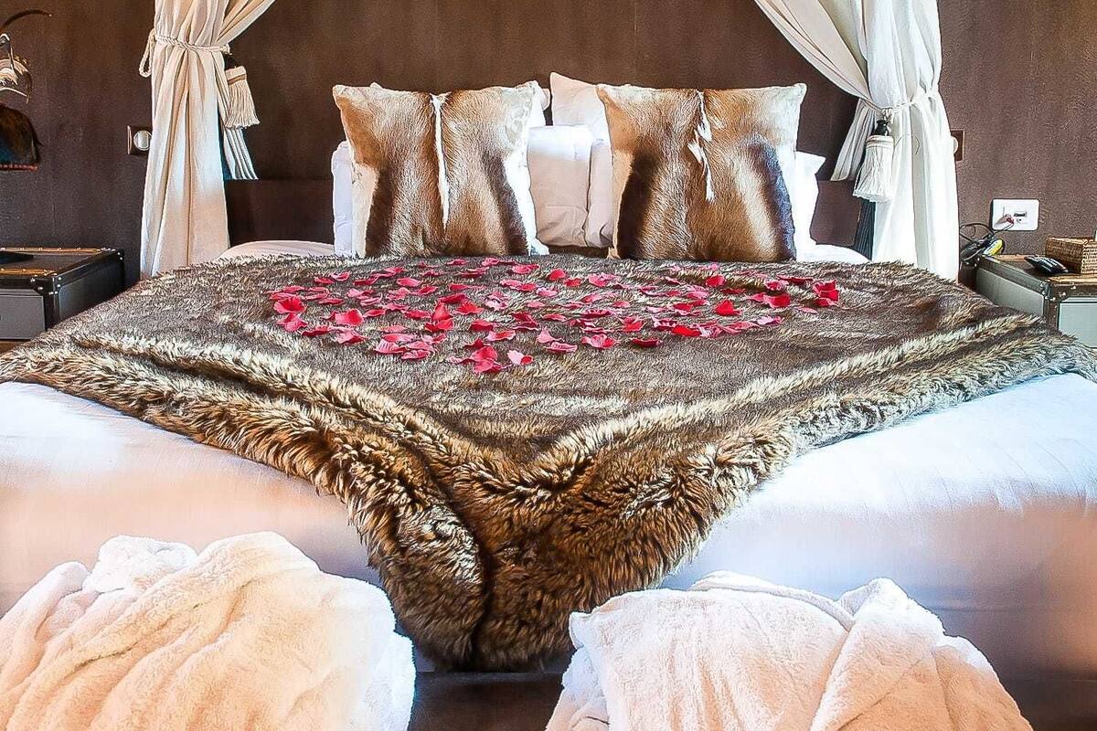 A bed with a fur throw, white pillows, and a canopy.