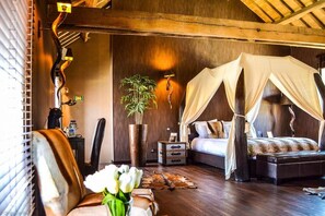 Un dormitorio con cama de dosel, una planta en maceta y suelo de madera.
