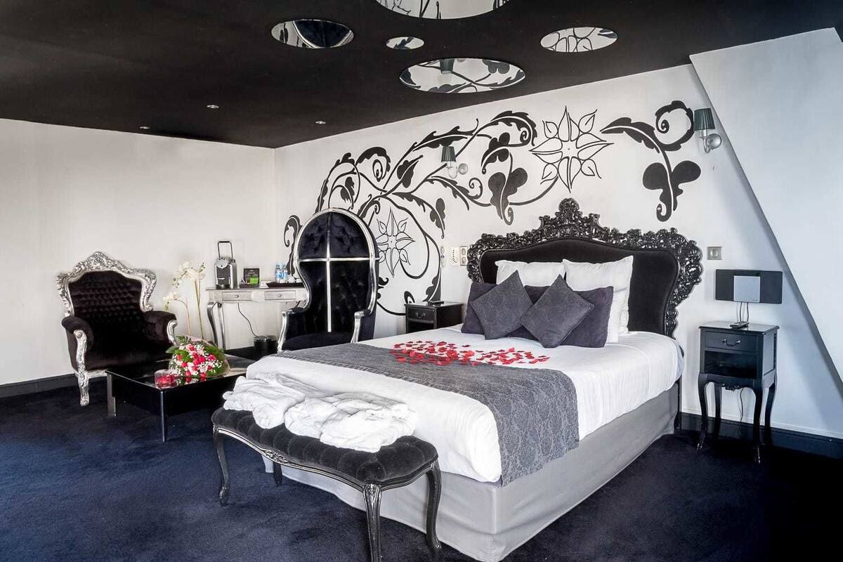 A modern bedroom with a large bed, a vanity, a chair, and a decorative wall.