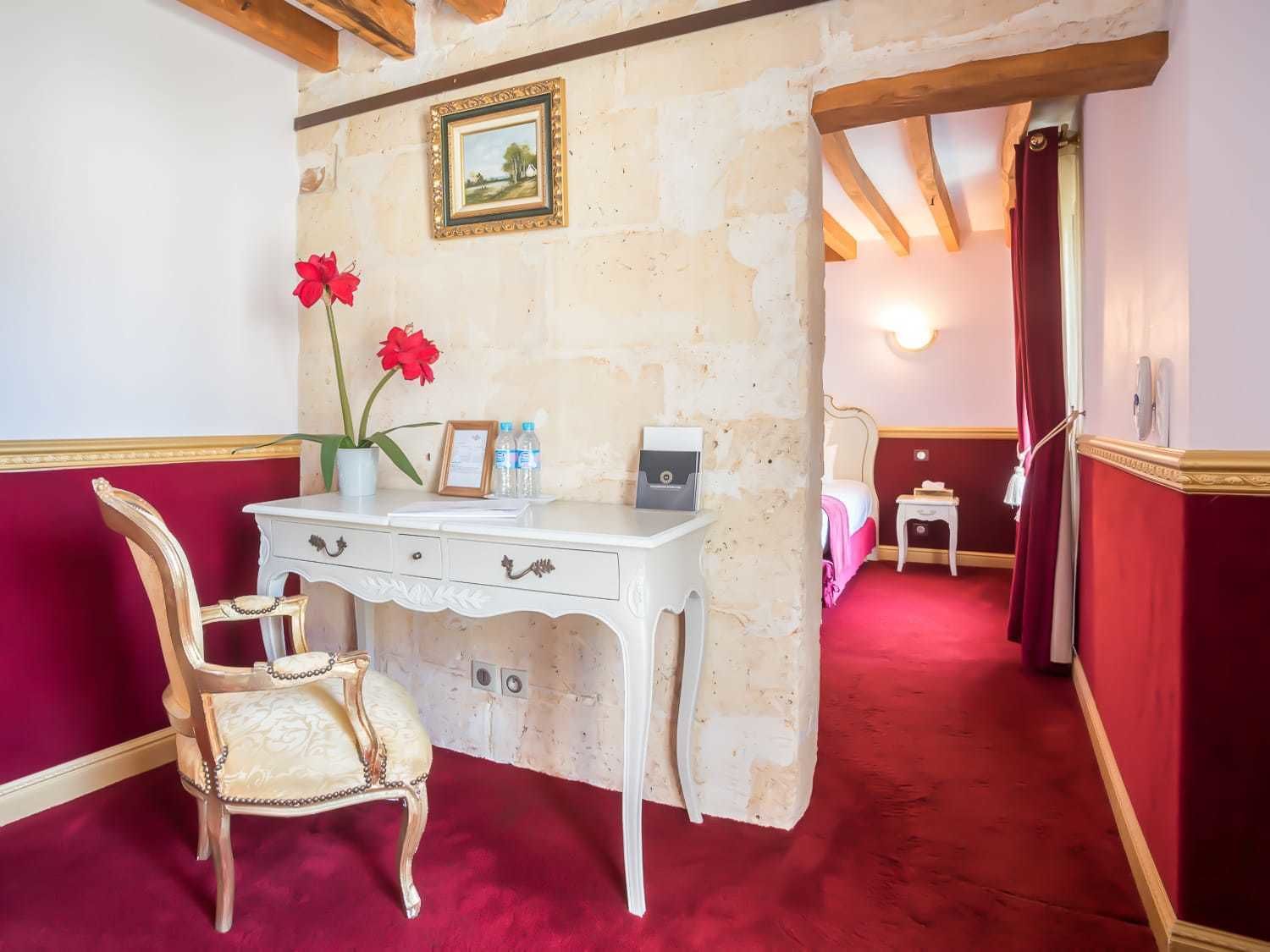 A room with a white desk, a chair, a bed, and a red carpet.
