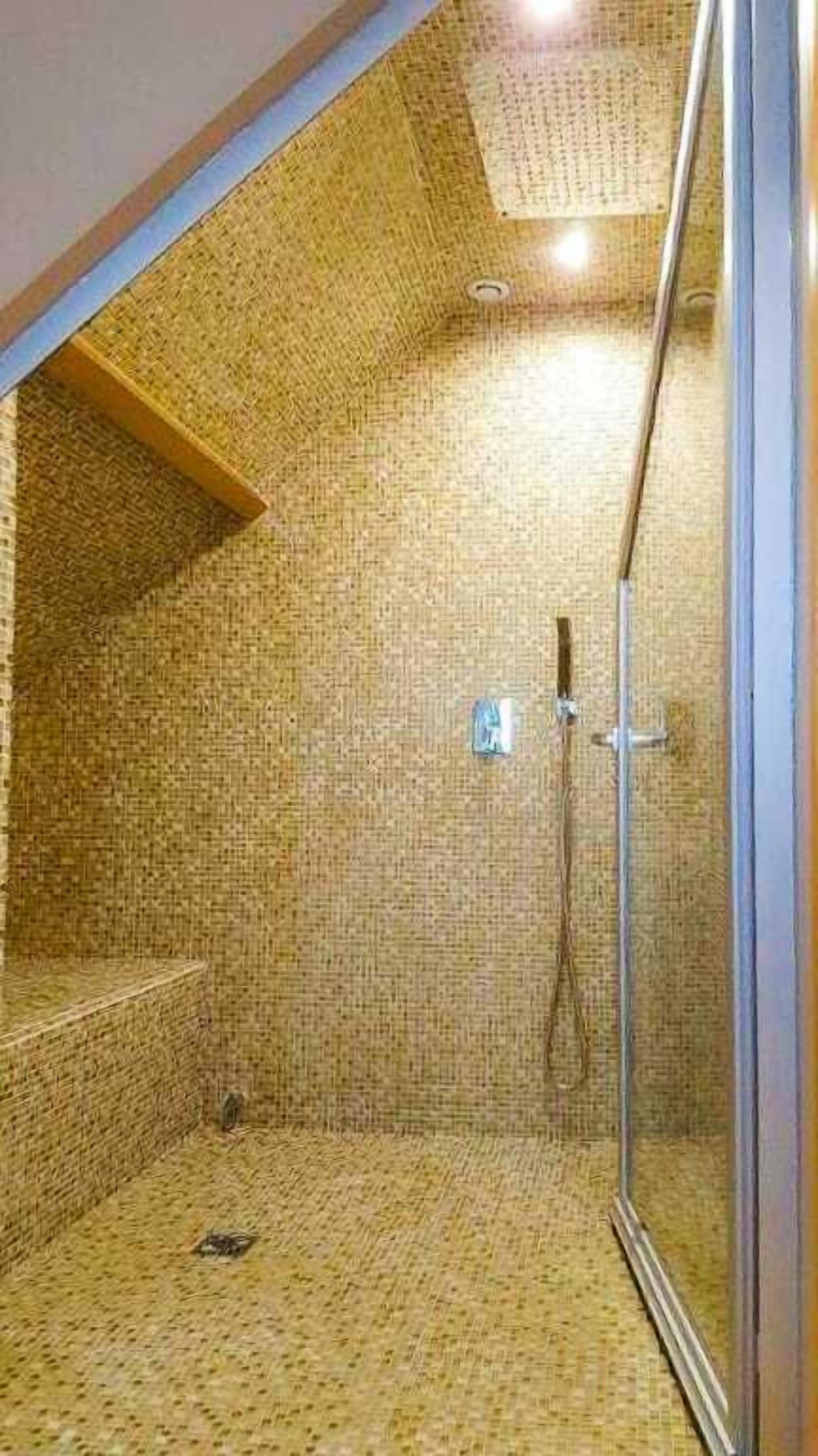 Un espacio de ducha con suelo de baldosas y puerta de cristal.