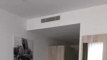 A hotel room with a bed, a desk, a chair, a wardrobe, and a window.