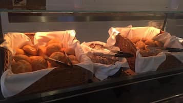 A buffet with various baked goods, including bread and pastries, displayed in wicker baskets.