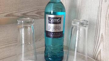 Una botella de Selters Classic sobre una superficie de madera, con dos botellas de vidrio vacías a cada lado.