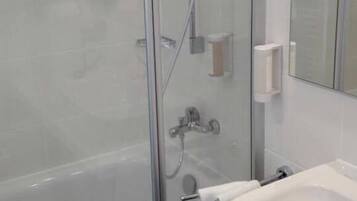 A modern bathroom with a glass-enclosed shower, a white sink, and a mirror.