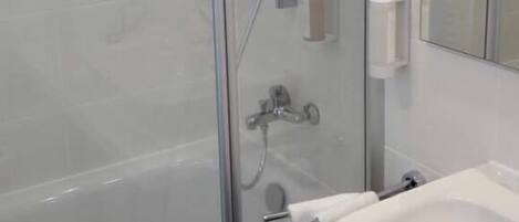 A modern bathroom with a glass-enclosed shower, a white sink, and a mirror.