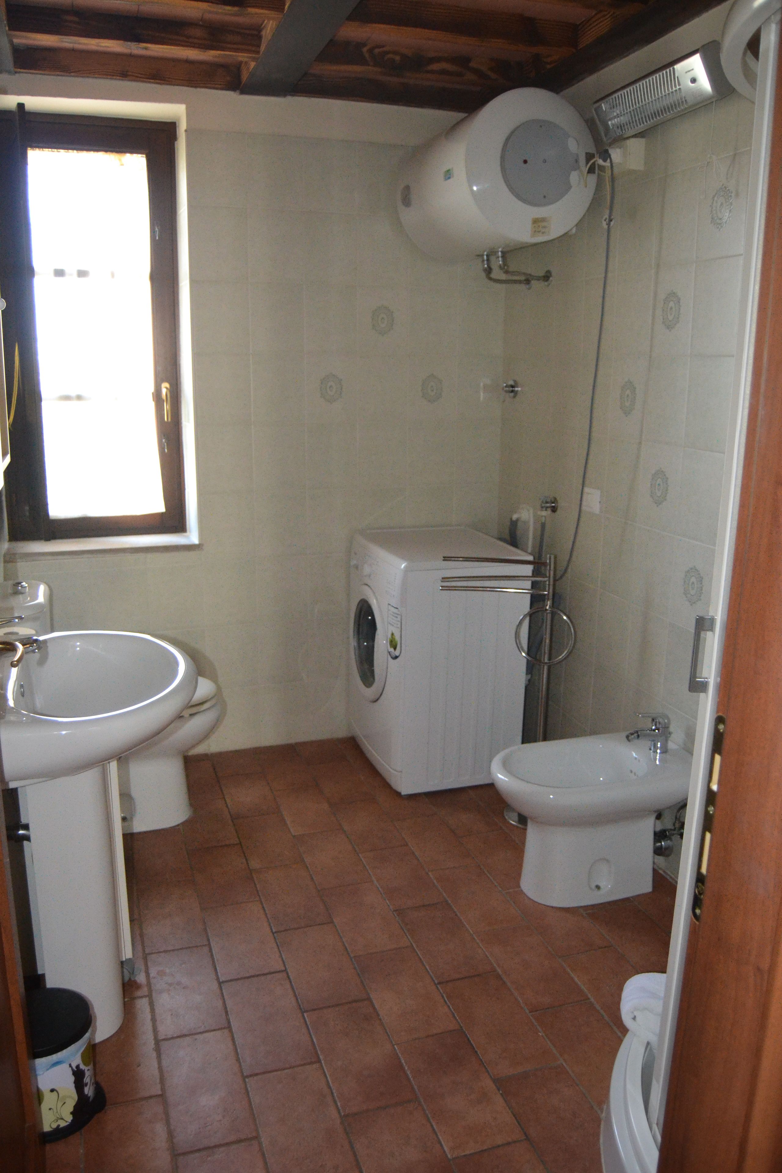 A compact bathroom with a sink, toilet, washing machine, and bidet.