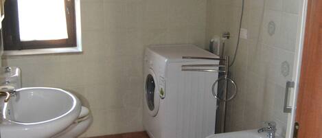 Un baño pequeño con lavamanos, inodoro, lavadora y bidé.