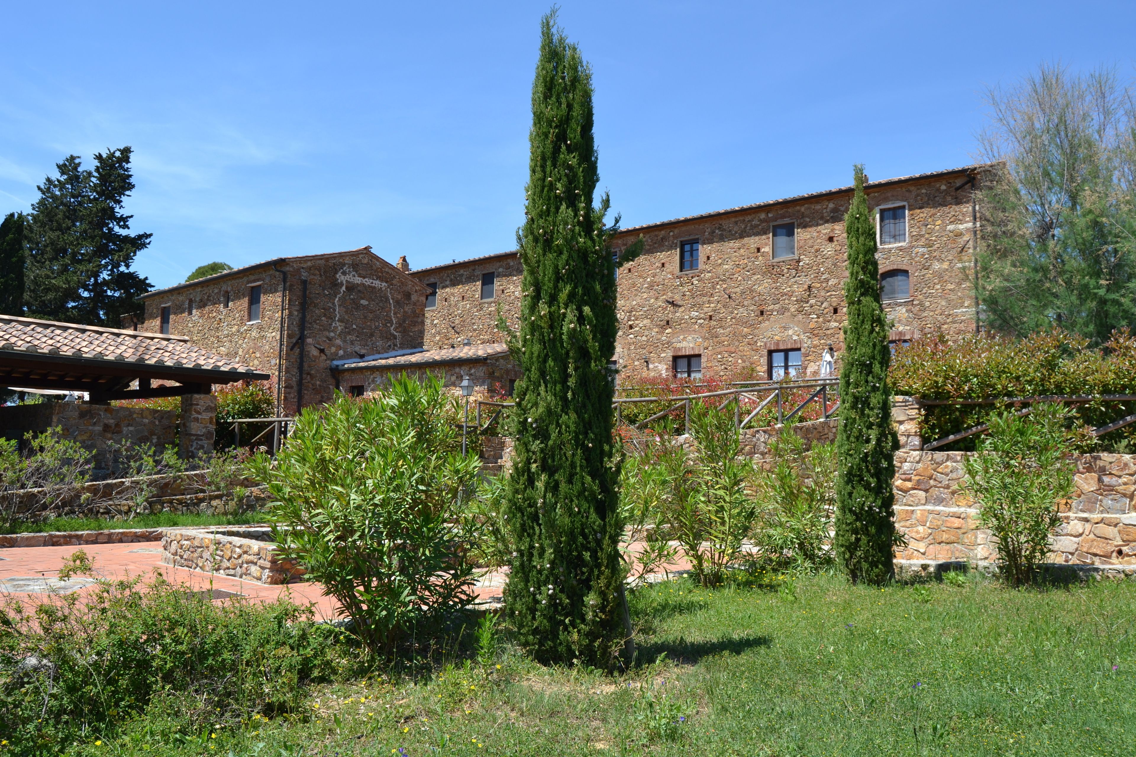 Un edificio de piedra con múltiples ventanas y un patio con plantas y un árbol alto.
