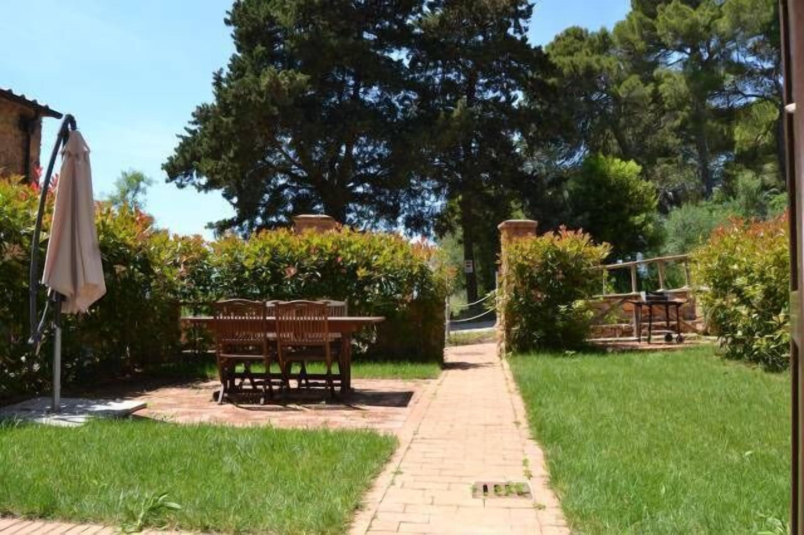 Un jardín con un sendero empedrado que lleva a una mesa y sillas de madera.