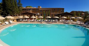 Una piscina al aire libre, sombrillas, sillones reclinables de piscina