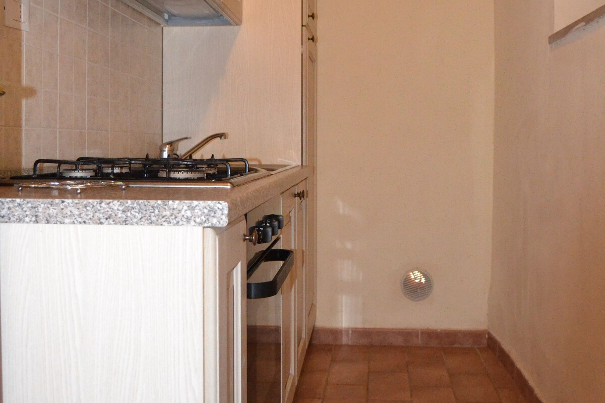 A kitchen with white cabinets, a gas stove, and a tiled floor.
