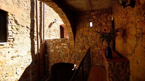 A stone-walled room with a wooden door, a small window, and a vase with flowers. - Antico Borgo Casalappi (Campiglia Marittima)