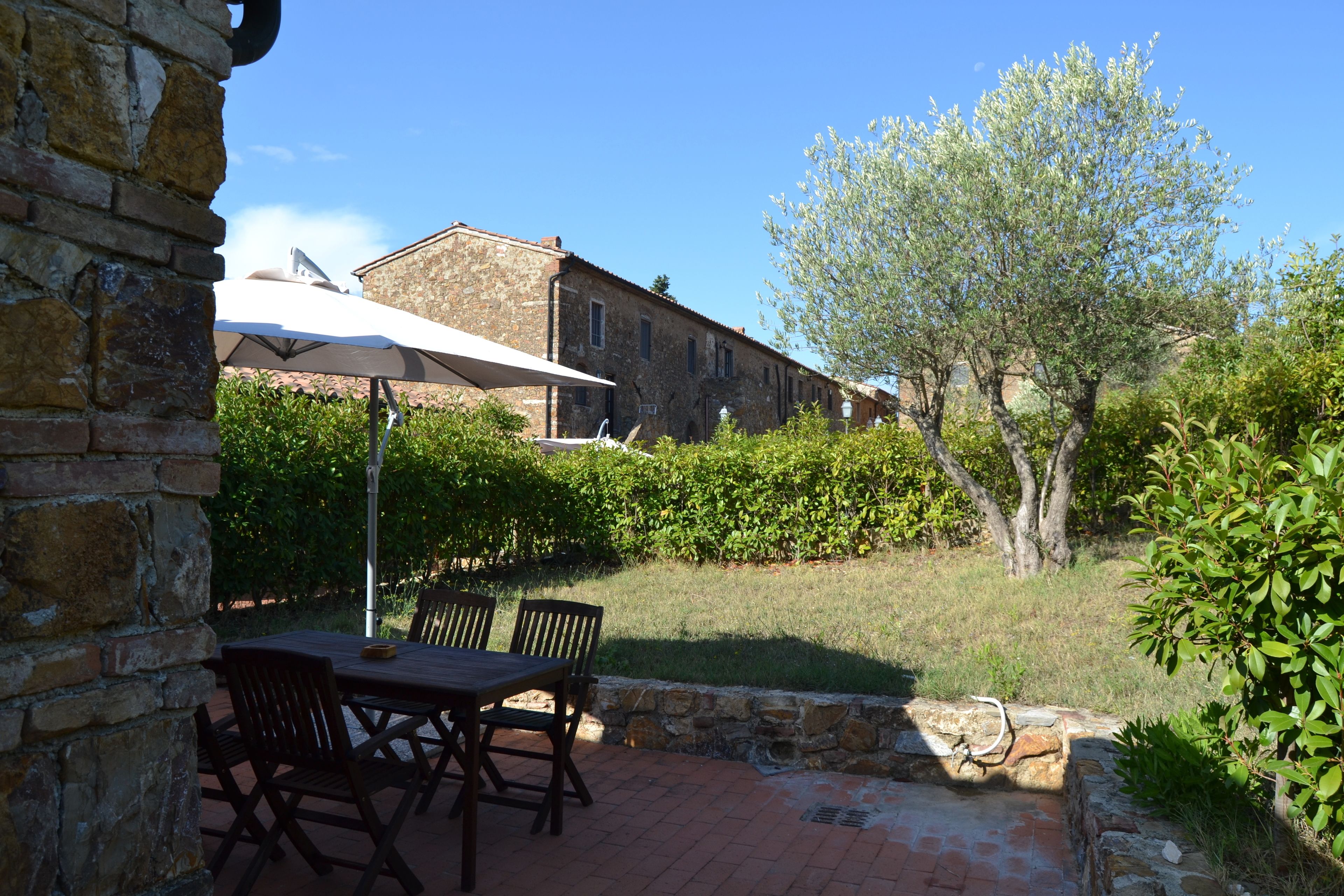 A patio with a table and chairs, a stone wall, and a building in the background.