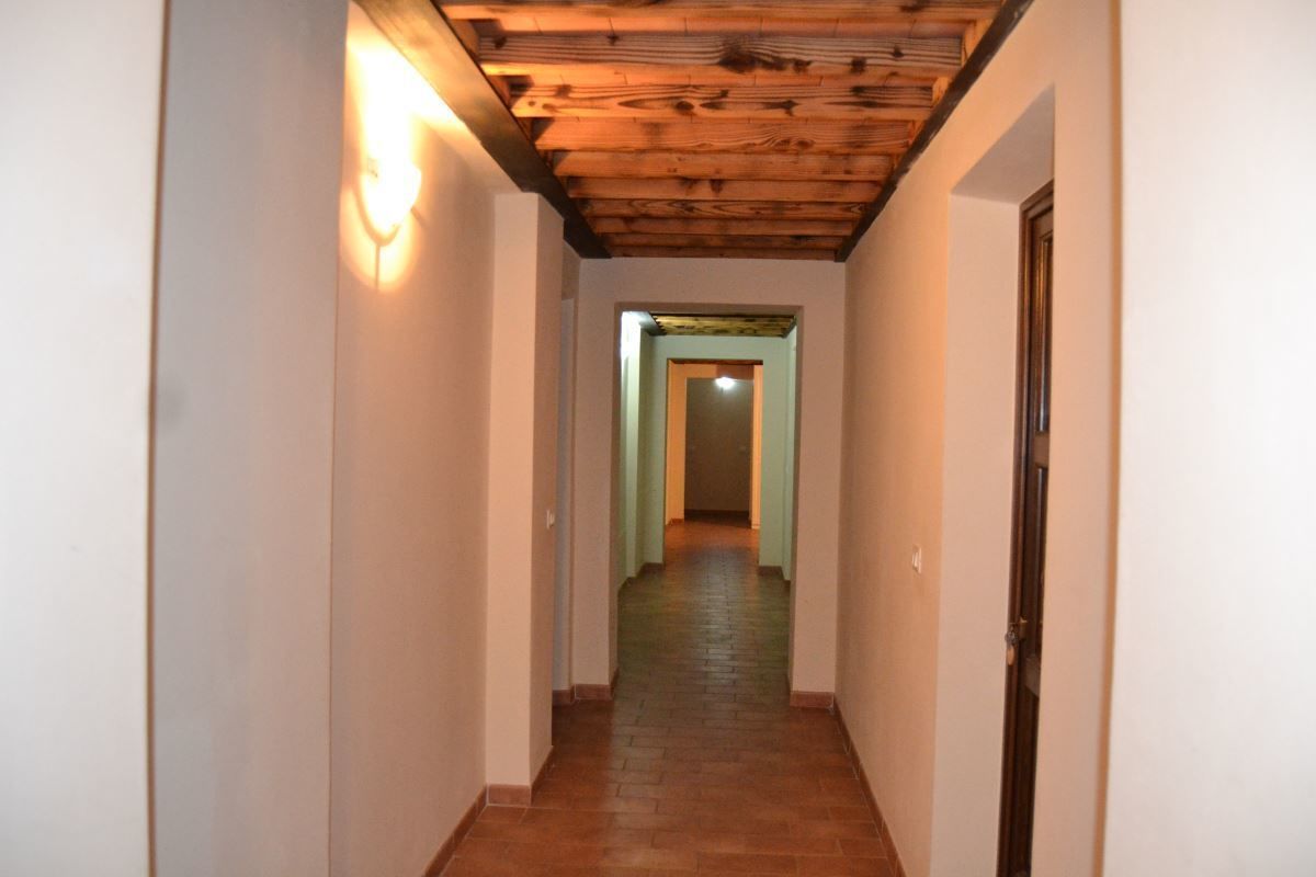 A narrow hallway with a wooden ceiling and a light fixture on the left wall.