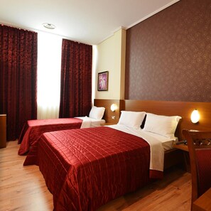 A hotel room with two beds, a wooden headboard, a desk, and a chair. - Hotel Austria (Tirana)