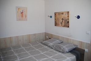 Un dormitori amb un llit, dos almoinos, una obra d'art penjada a la paret i un tablix.