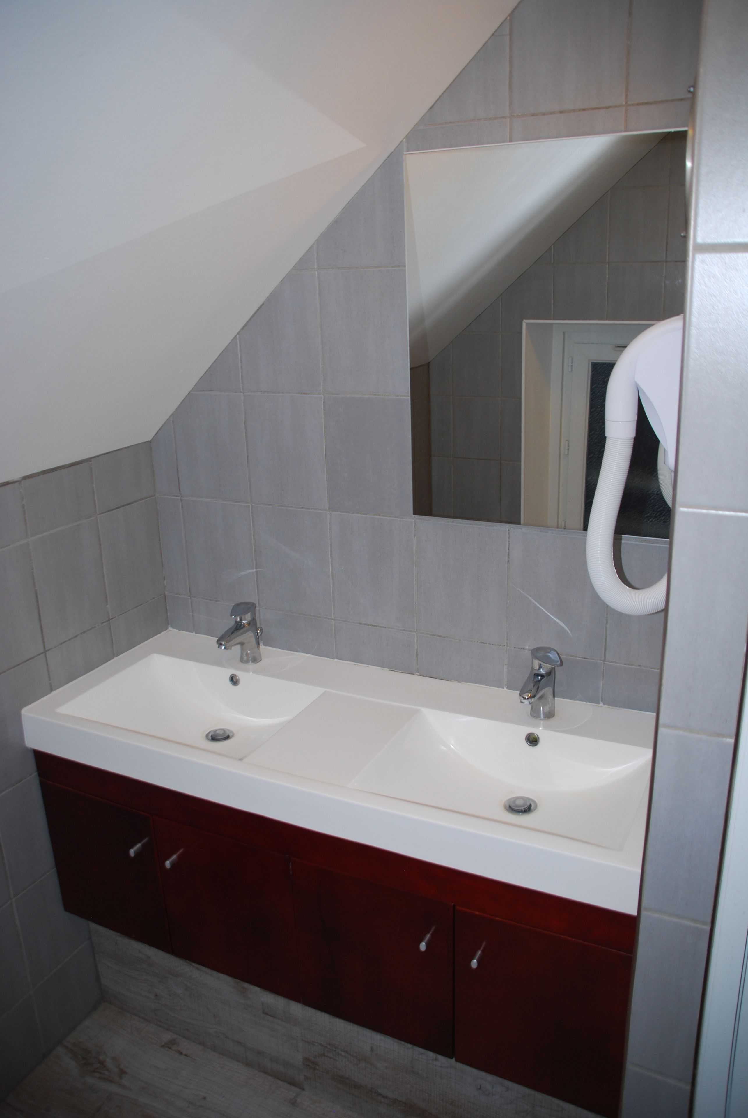 Une salle de bain avec deux lavabos, un miroir et un porte-serviettes.