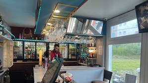 Uma área de bar com um bartender, um registrador de caixa e uma gaveta de dinheiro cheia de notas.