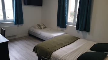 Une chambre avec deux lits, un téléviseur fixé au mur et un bureau.