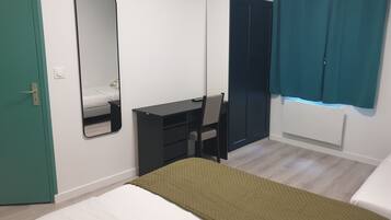 A bedroom with a bed, a desk, a chair, a wardrobe, and a mirror.