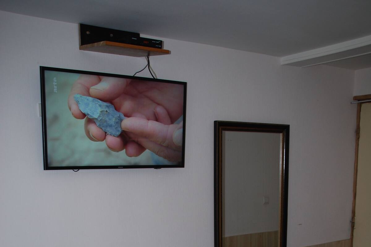 Une chambre à coucher avec un lit, un téléviseur fixé au mur et un miroir.