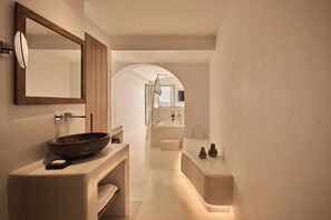 A modern bathroom with a large mirror, a bowl sink, and a walk-in shower.