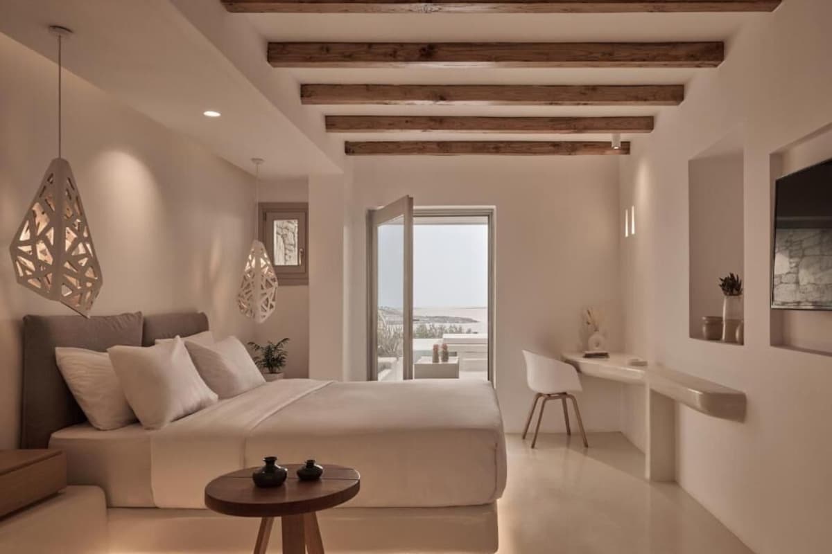A modern bedroom with a bed, bedside table, and a view of the outdoors.