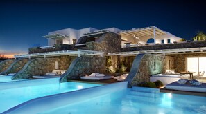 Un resort moderno con piscina, paredes de piedra y zonas de estar al aire libre.