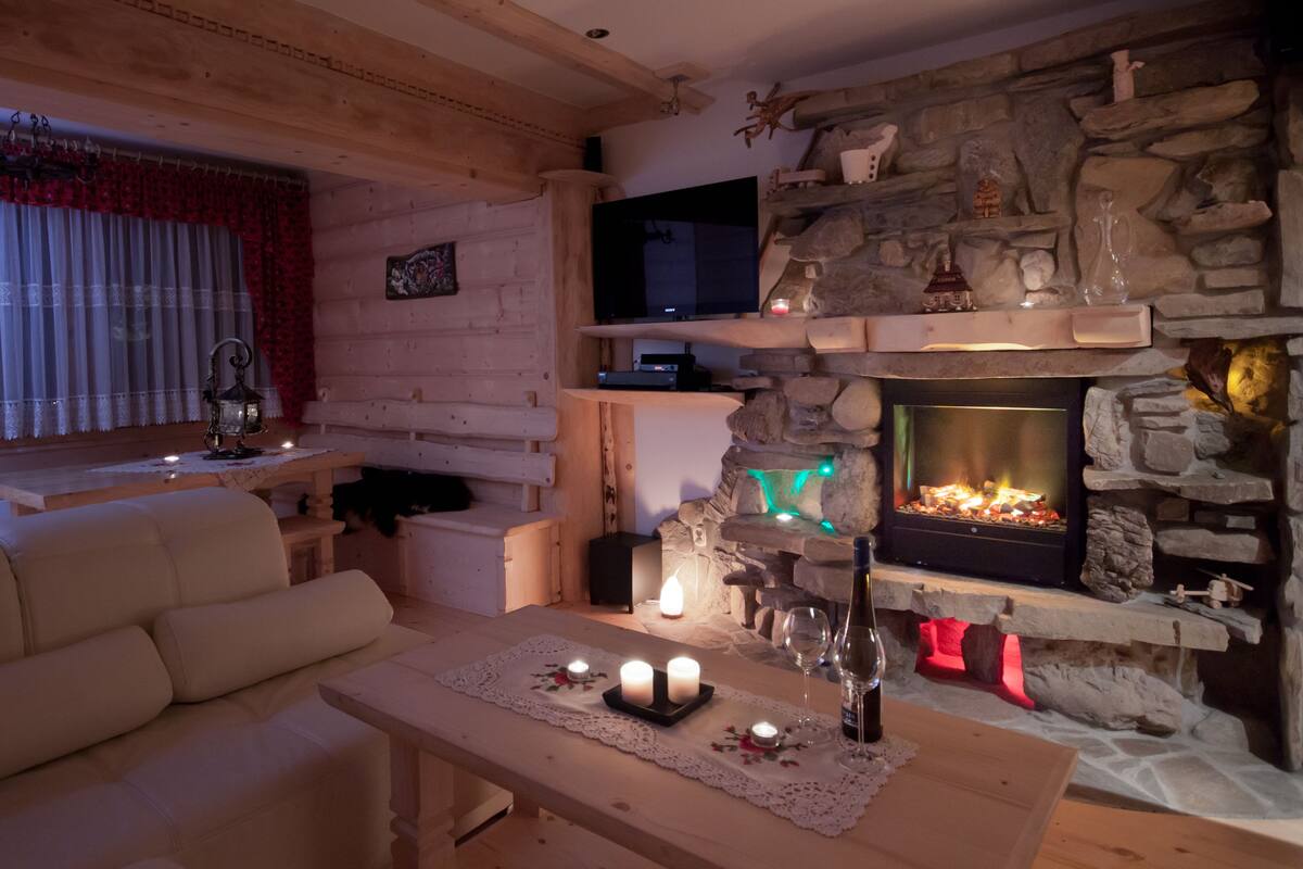 A cozy living room with a stone fireplace, a flat-screen TV mounted above it, and a comfortable sofa.