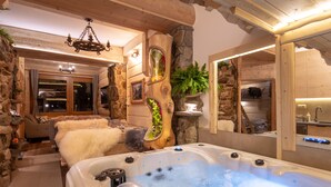 Ein Wellnessbereich mit Whirlpool, Steinwänden, Holzbalken und einem Spiegel, der den Raum widerspiegelt.
