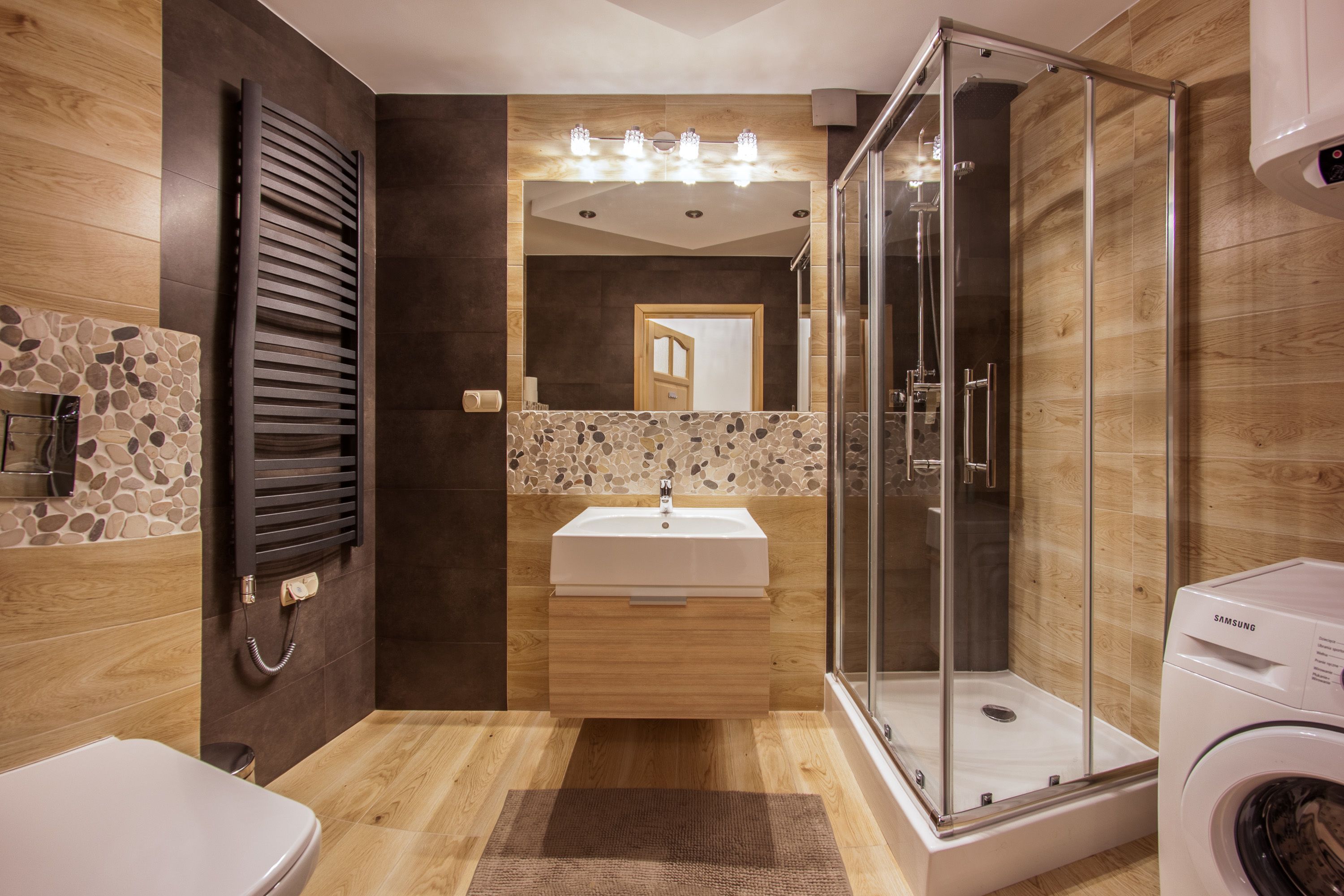 A modern bathroom with a shower, toilet, and washing machine.