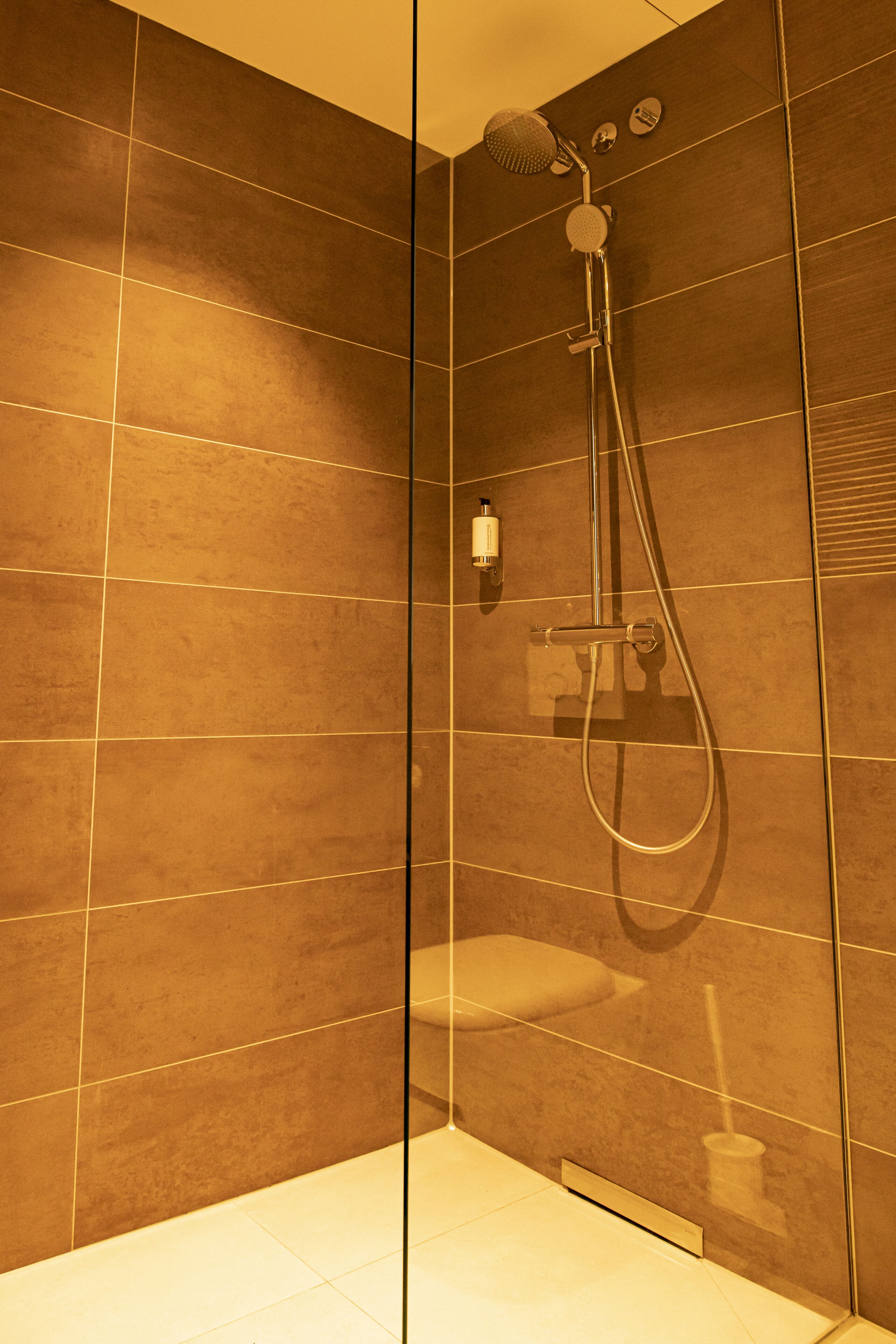 Une salle de bain moderne avec une douche, des murs carrelés et des toilettes.