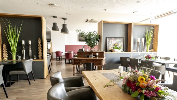 A modern dining area with a wooden table, leather chairs, and a floral centerpiece. - Hotel Campo (Renningen)