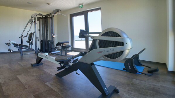 A gym with various exercise equipment, including a rowing machine and a leg press.