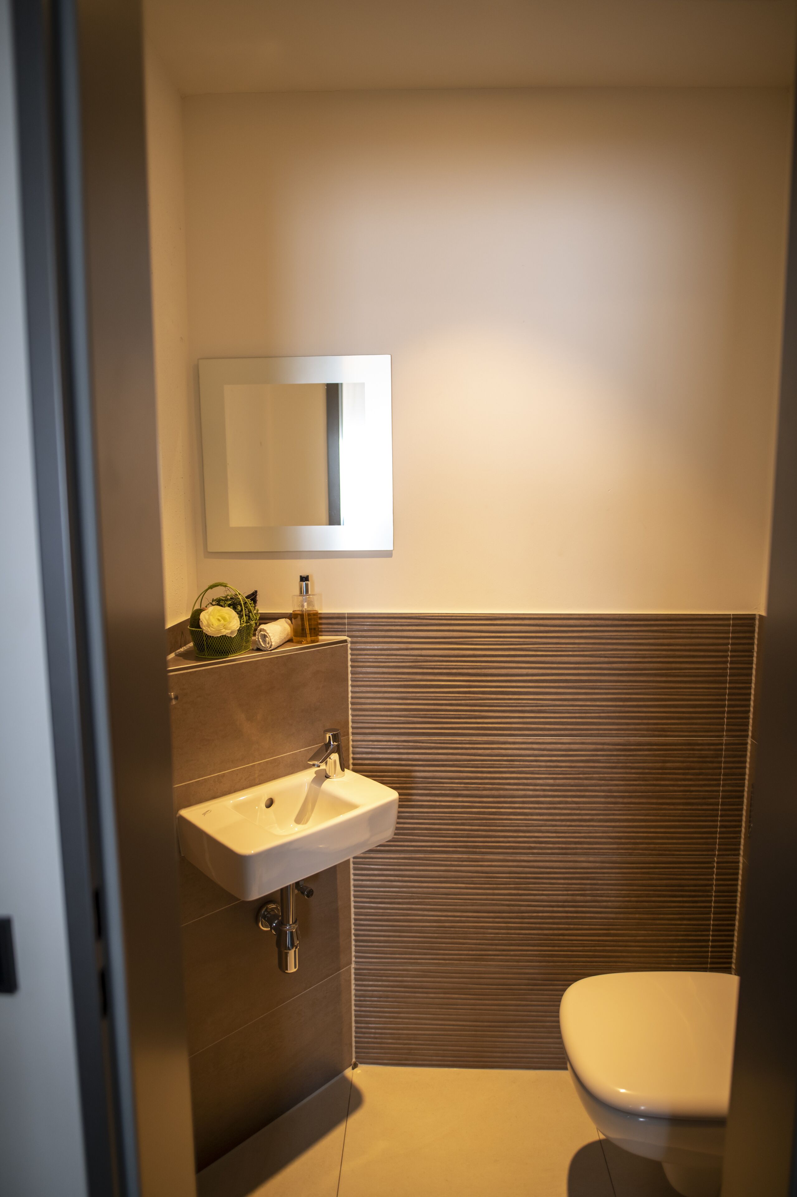 A modern bathroom with a sink, mirror, and toilet.