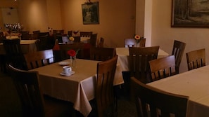 Un restaurante con varias mesas y sillas, algunas adornadas con flores.